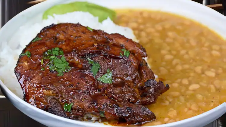 Close-up of perfectly cooked pork chop with beans and white rice