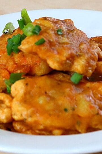 Authentic Puerto Rican bacalaitos (codfish fritters) garnished with sliced green onions on a white plate