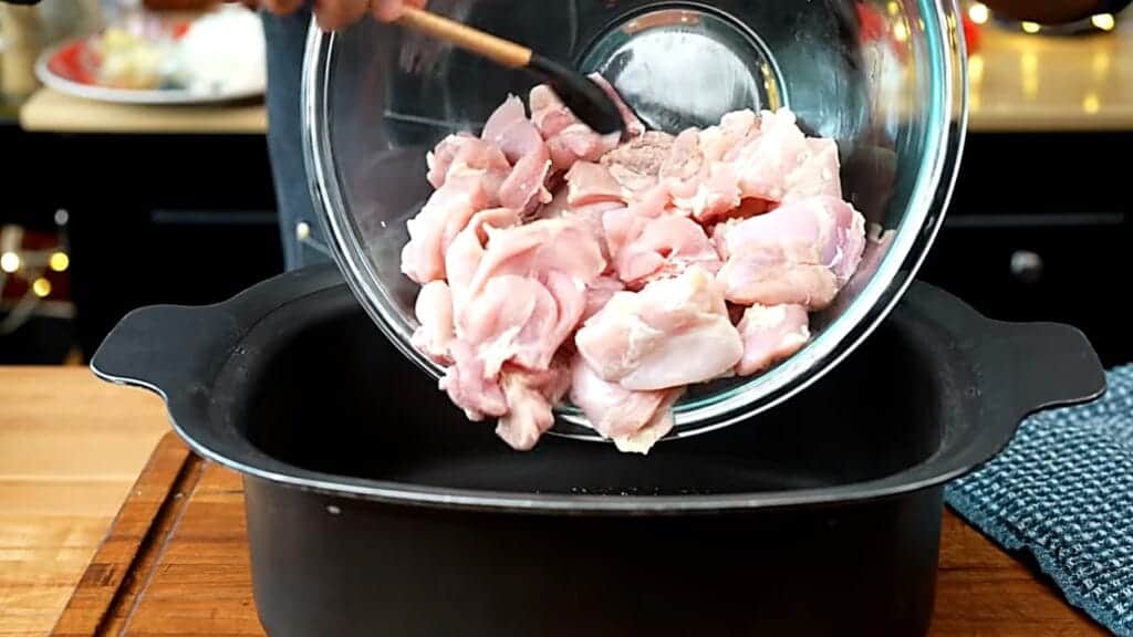 Adding seasoned chicken to the slow cooker for butter chicken