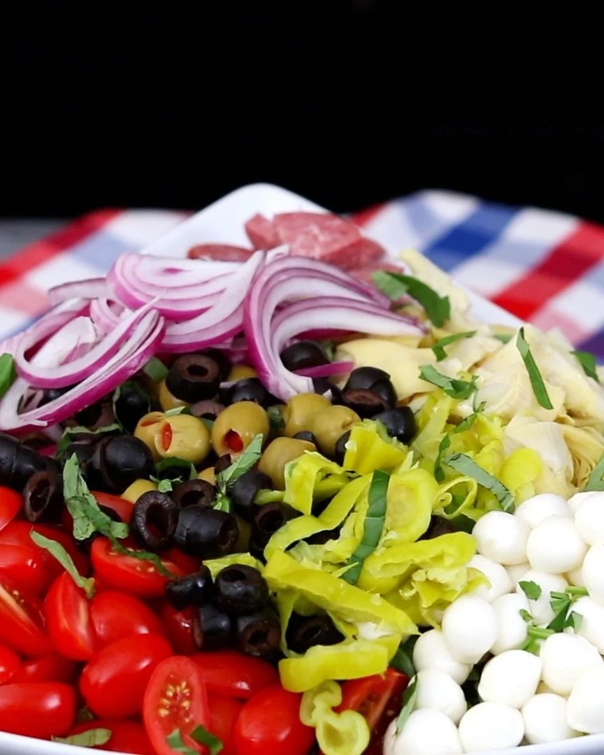 Colorful platter of fresh vegetables and olives with cherry tomatoes, onions, olives, lettuce, and mozzarella
