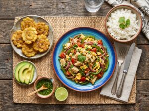 Dominican Bacalao con Huevos served alongside white rice, tostones and avocado slices on a rustic wooden table