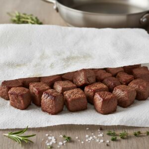 Braised beef being patted dry with paper towels before frying