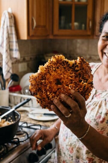 Dominican man holding up crispy concon rice dome from caldero