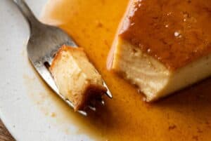 Close-up slice of flan dominicano with amber caramel sauce pooling