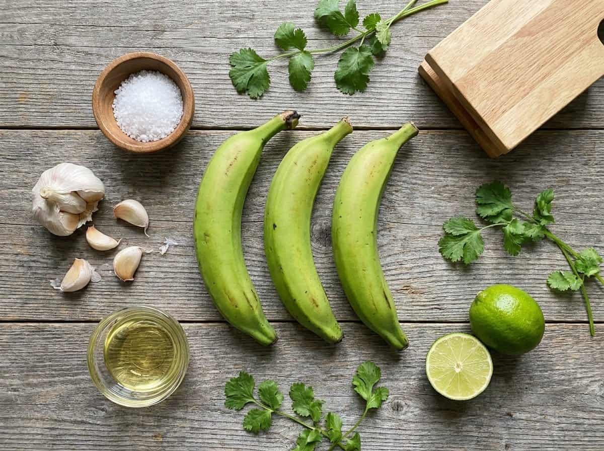 Flat lay of green plantains, garlic, sea salt, limes, cilantro and a tostonera press for Dominican tostones