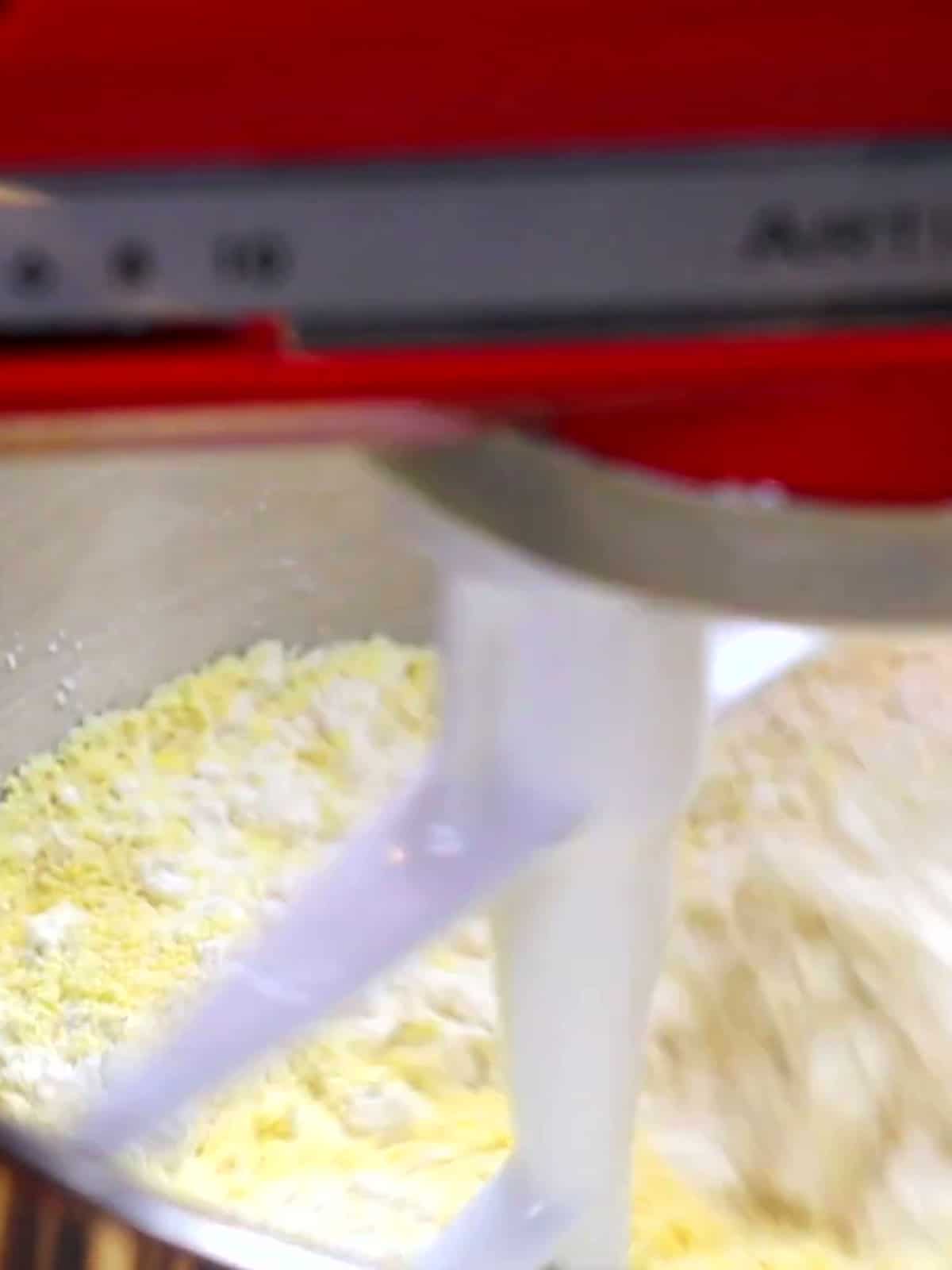 Cornmeal masa being mixed for guanimos in a stand mixer