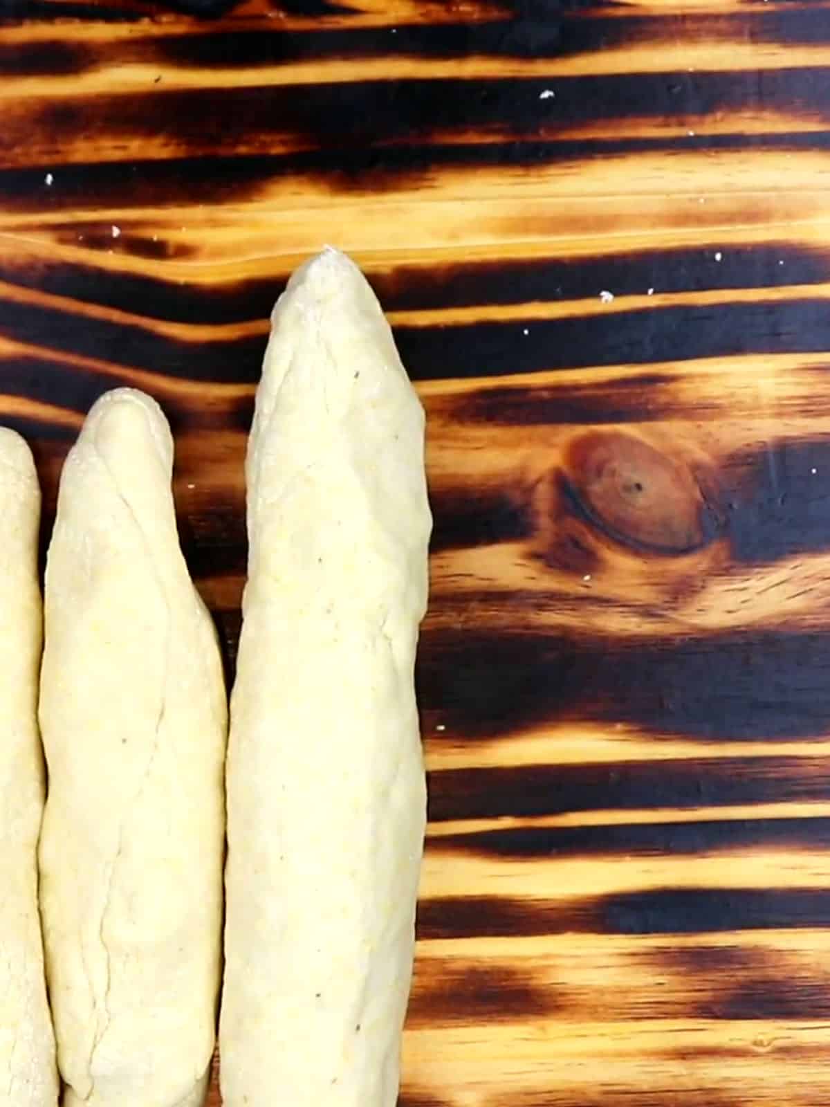 Shaped guanimos dough on a wooden cutting board ready for wrapping