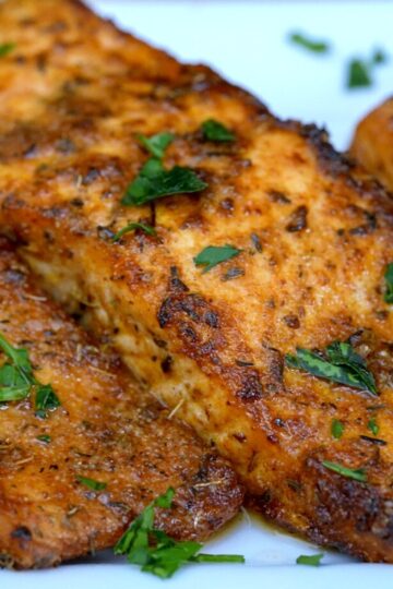 Perfectly crispy air fryer salmon fillets with blackening seasoning and fresh parsley on a white plate