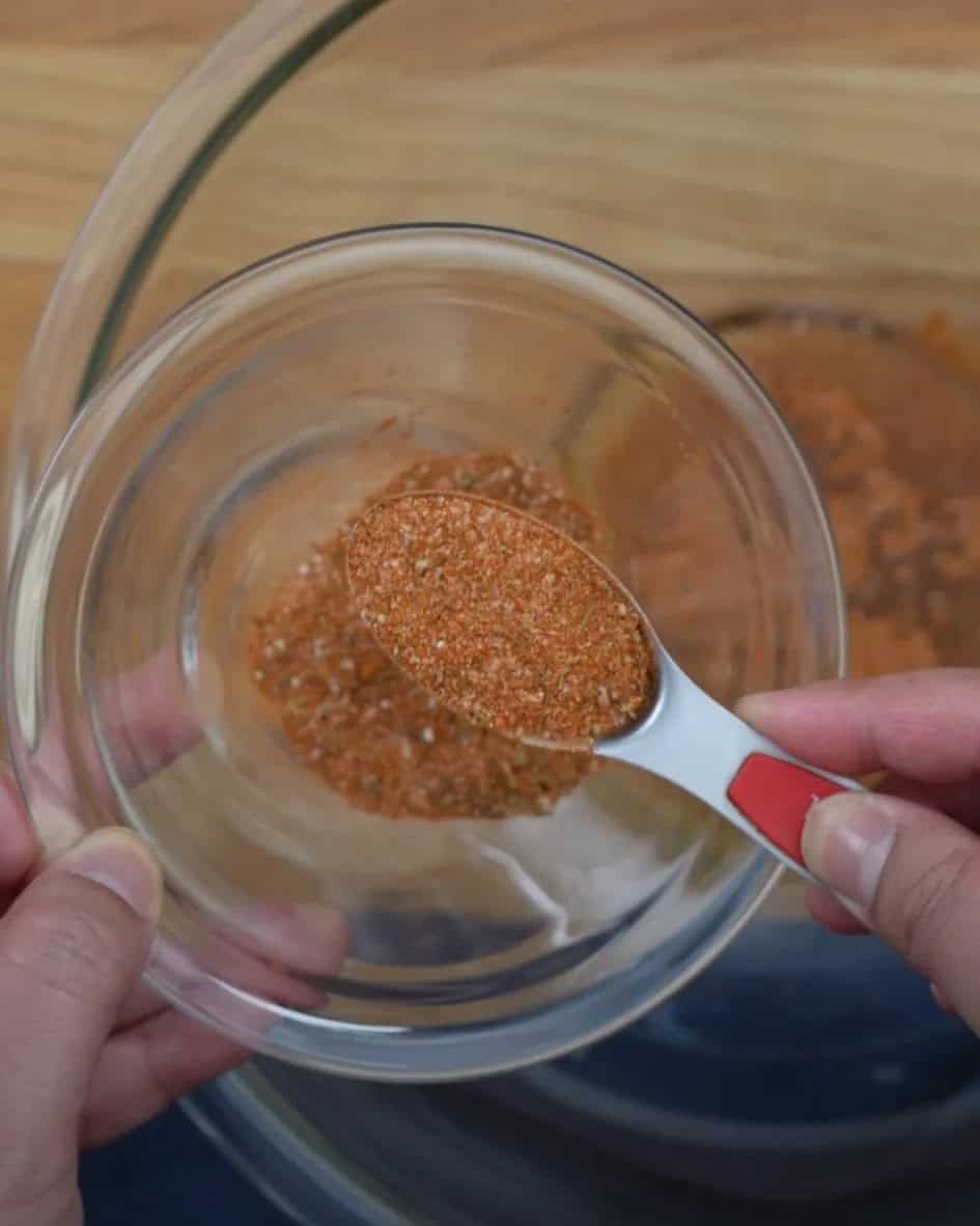 Homemade blackening seasoning blend in a glass bowl with a measuring spoon