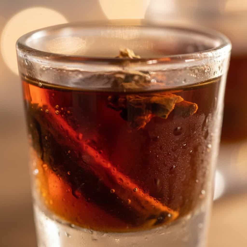 Close-up of mamajuana shot glass with dark amber liquid