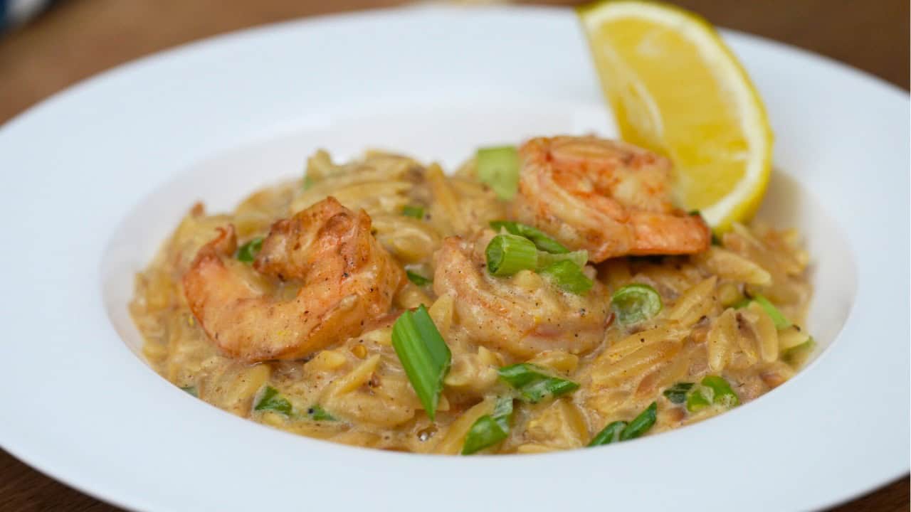 one pan shrimp and lemon orzo in a white bowl with lemon wedge