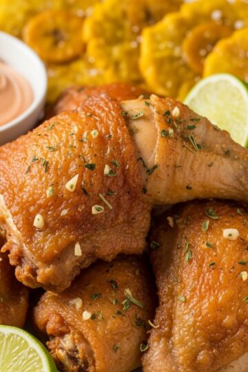 Crispy Dominican fried chicken pieces on a rustic plate with lime and mayo-ketchup