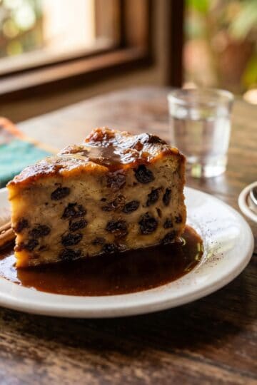 Slice of Dominican pudin de pan served on white plate with caramel sauce and coffee
