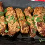 Air fryer country style pork ribs on a black platter with fresh parsley