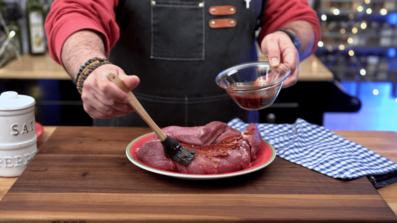 brushing gochujang glaze on raw pork tenderloin