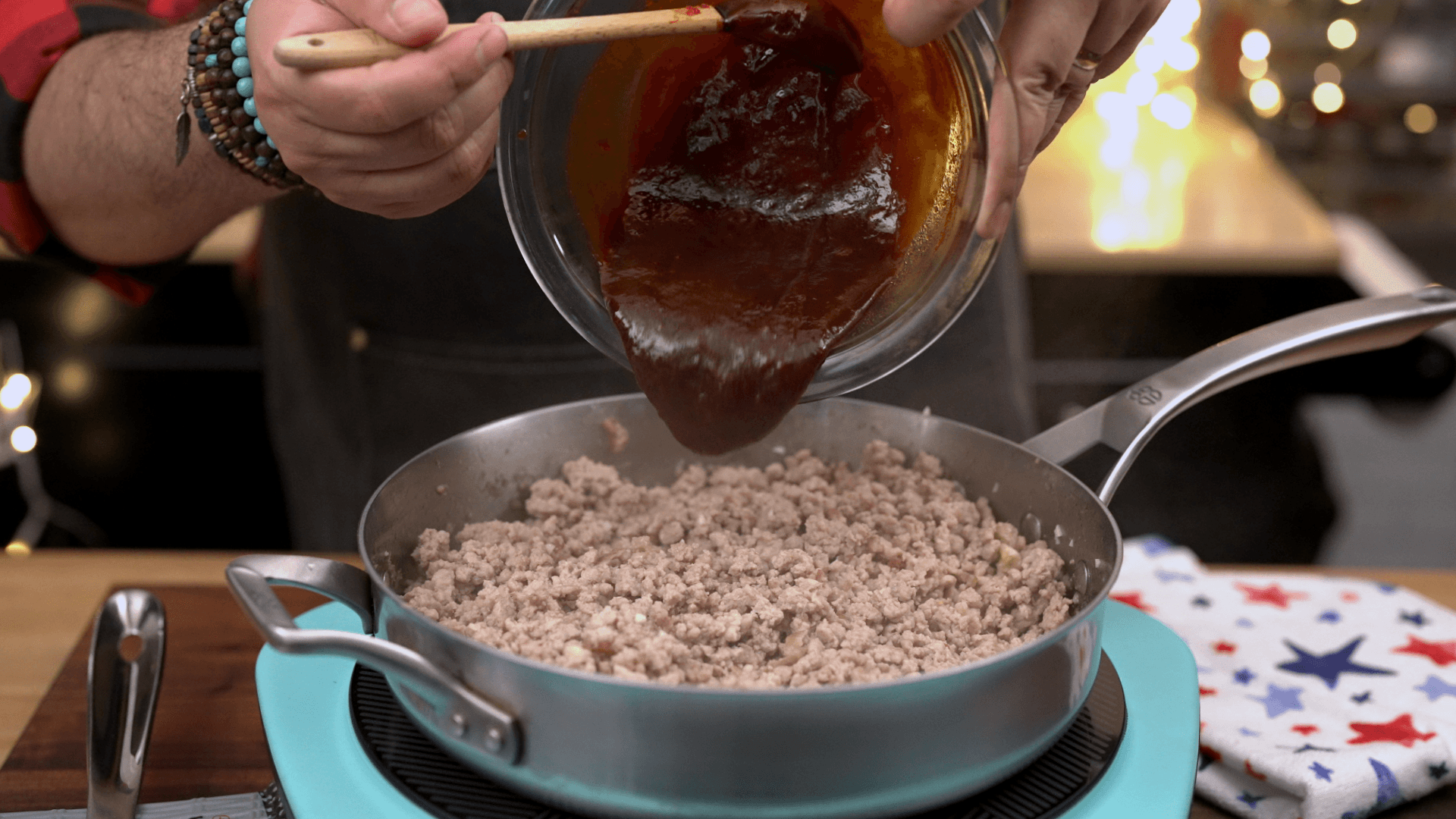 Pouring gochujang sauce over browned ground pork in a skillet for Korean-inspired pork rice bowls