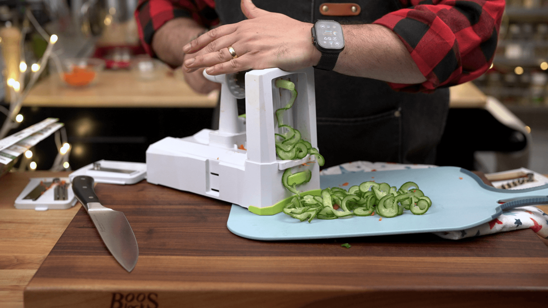 Spiralizing mini cucumbers into ribbon rings on a wood cutting board for Korean pork bowls