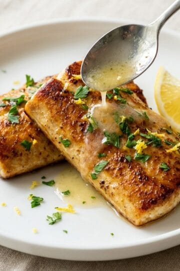 Pan-seared mahi mahi fillets topped with lemon garlic butter sauce and parsley on a white plate