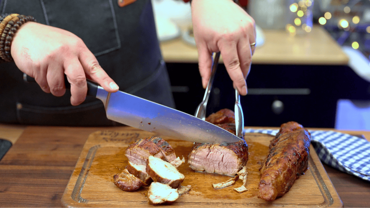 slicing gochujang glazed pork tenderloin on cutting board