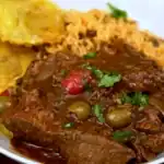 Tight-crop plated slow cooker Dominican pot roast with olives, rice, and tostones