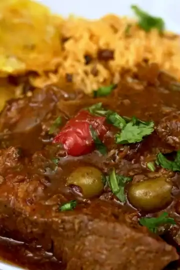Tight-crop plated slow cooker Dominican pot roast with olives, rice, and tostones