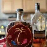 Mamajuana — The Dominican Drink That You Have to Try Mamajuana bottle with Dominican bark and herbs, Barceló rum in background