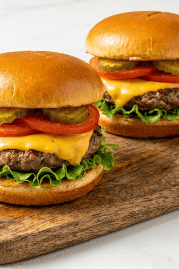 Air fryer cheeseburgers with melted American cheese, lettuce, tomato, and special burger sauce on a cutting board
