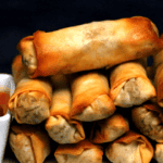Crispy golden air fryer spring rolls stacked on a plate with sweet chili dipping sauce
