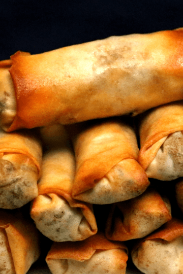 Crispy golden air fryer spring rolls stacked on a plate with sweet chili dipping sauce