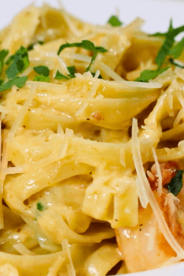 Creamy shrimp alfredo with fettuccine, parmesan, and parsley in a white bowl