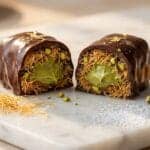 Dubai chocolate bar cross-section showing layers of dark chocolate, crispy kataifi pastry, and pistachio cream filling