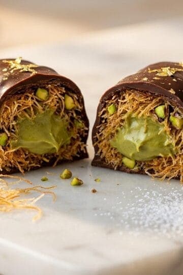 Dubai chocolate bar cross-section showing layers of dark chocolate, crispy kataifi pastry, and pistachio cream filling