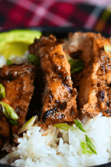 Honey garlic grilled chicken sliced over white rice with avocado, green onion, and narutomaki in a bowl