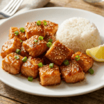 Air Fryer Honey Garlic Salmon Bites Honey garlic salmon bites in an air fryer basket, golden brown with sticky glaze, garnished with sesame seeds and green onions