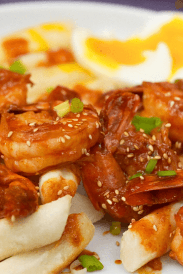 Korean gochujang shrimp with crispy rice cakes and a jammy soft-boiled egg, topped with sesame seeds and green onion