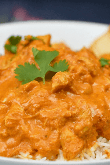 Slow cooker chicken tikka masala in a creamy tomato sauce served over basmati rice with naan and fresh cilantro