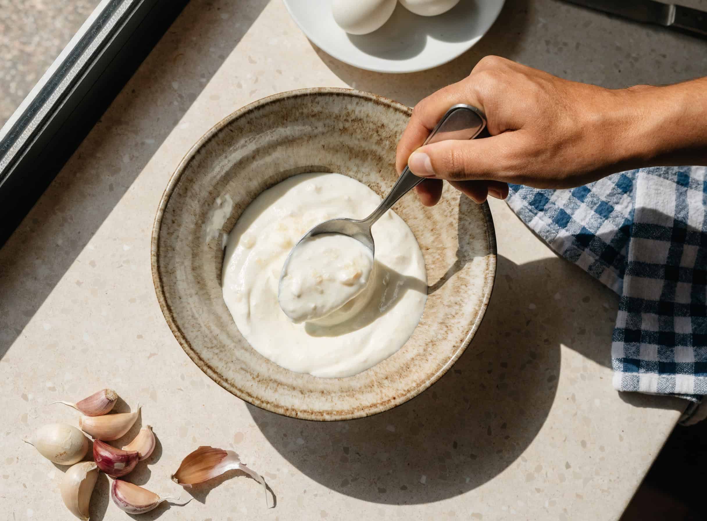 Spreading garlicky yogurt base in a bowl for Turkish eggs